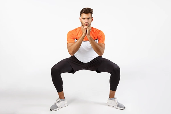 Man in squat position to strengthen legs and burn fat