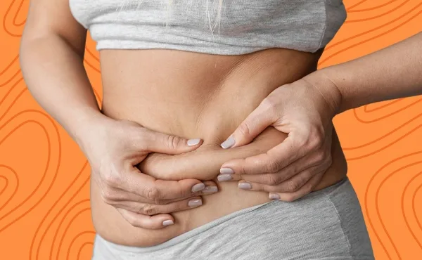Woman squeezing lower-belly skin to highlight stubborn cellulite and fat targeted by retinol and advanced cellulite treatments