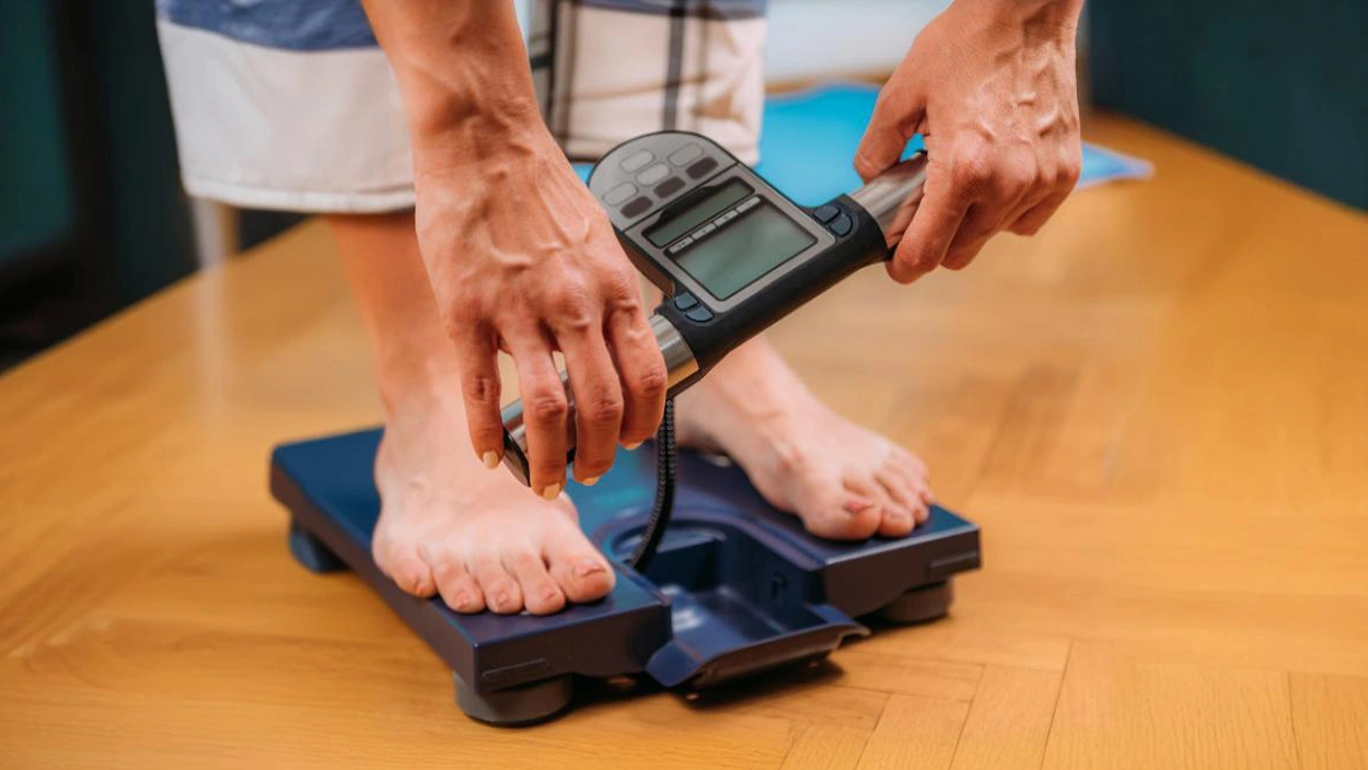 Person using a digital body composition scale with handles for advanced BMI and body metrics measurement
