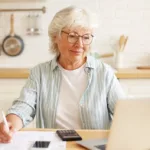 Senior woman calculating her BMI using a laptop in a kitchen setting