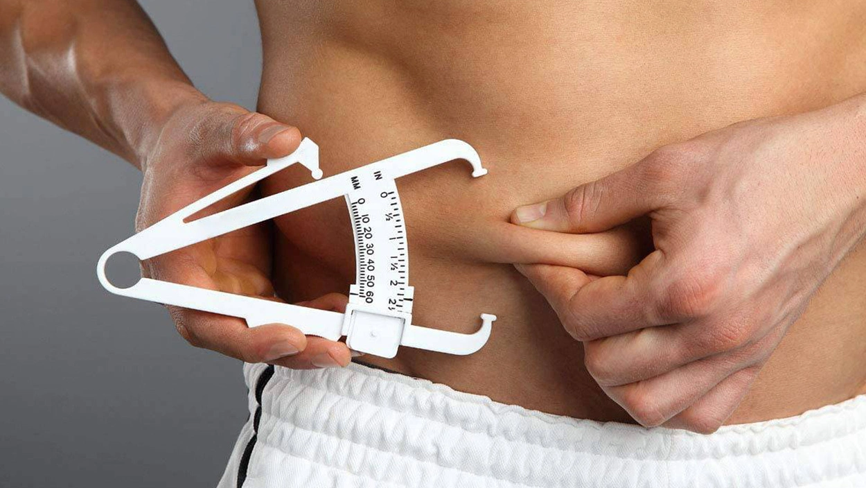 Person using skinfold calipers to measure abdominal body-fat fold for BMI and body-fat calculator article.