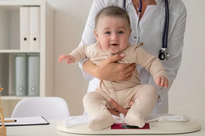 Pediatrician weighing a baby during a growth checkup