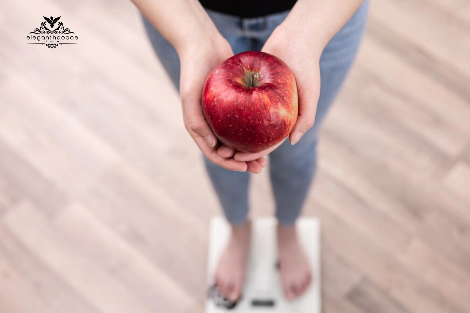 Overhead of woman on scale holding red apple—visual cue for BMI, “apple-shaped” visceral fat risk