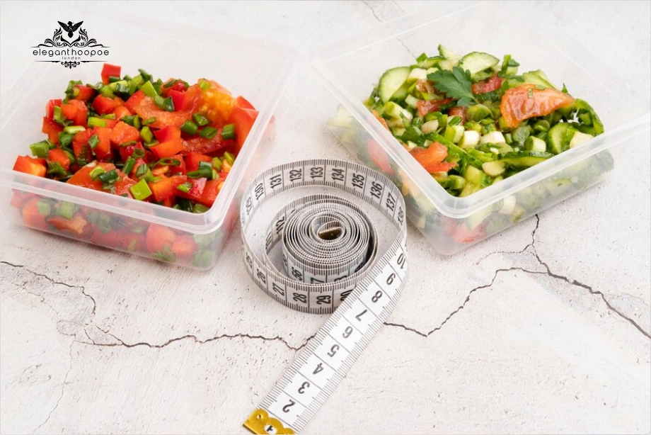Two meal prep containers filled with healthy vegetables and salmon, next to a measuring tape.
