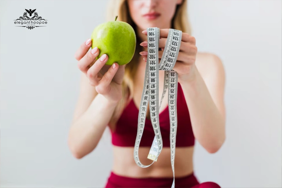 Woman in workout clothes holding apple and measuring tape for weight control.
