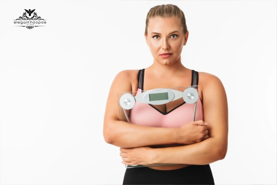 Athletic woman holding a digital scale to her chest, questioning results. 