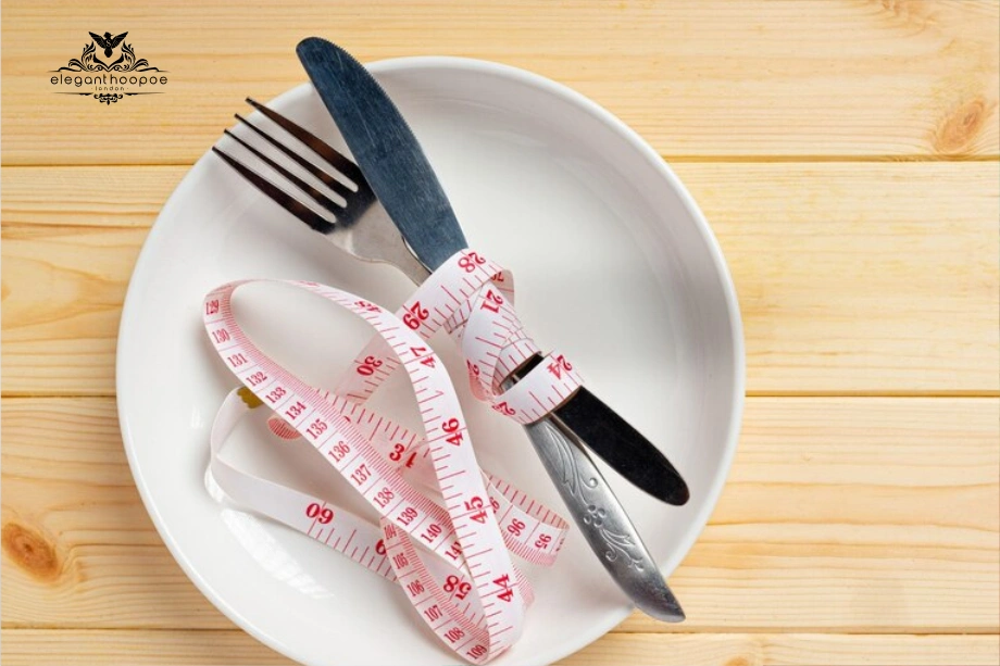 White plate, knife, fork and pink measuring tape highlighting portion control when lowering BMI and trimming body fat