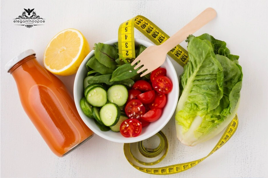 Bowl of vegetables, juice, lemon, and measuring tape on a white table