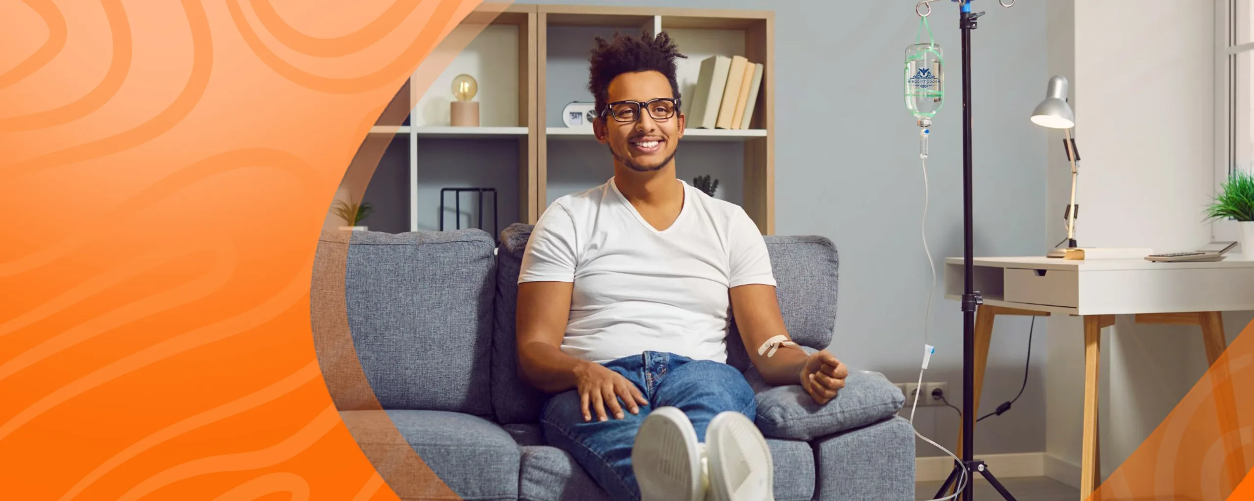 Man receiving IV therapy on a couch at home, with IV drip and wellness setup in a modern living room.