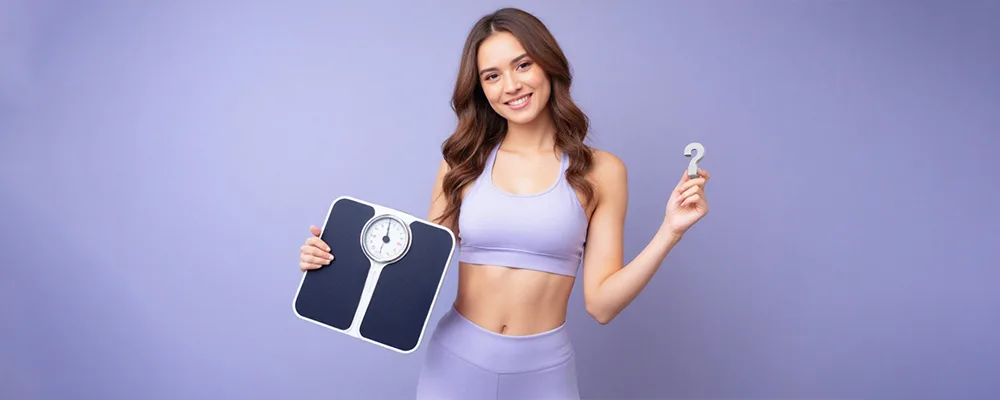 Woman holding a bathroom scale and a question mark, symbolizing a personalized ideal body weight calculator for men and women