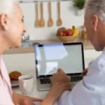 Seniors reviewing health infor on laptop in kitchen
