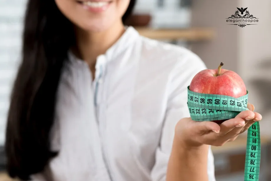Woman holding a red apple wrapped with a green measuring tape, symbolizing BMI tracking and health awareness.