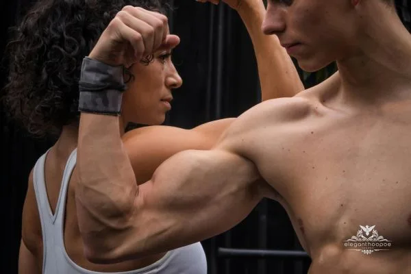 Close-up of a woman and a man flexing muscles, highlighting muscle mass differences