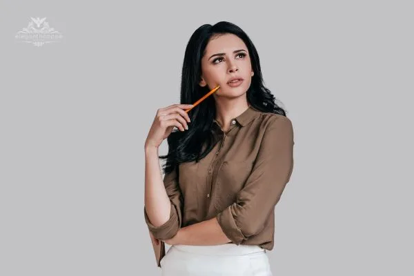 A professional woman in a brown shirt holding a pencil to her chin, pondering innovative body composition metrics