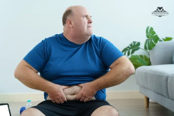 Person in blue shirt and black shorts holding their abdomen to illustrate body mass index evaluation