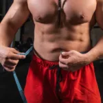 Fit individual measuring waist circumference with tape to assess fat-to-muscle ratio and optimize body composition