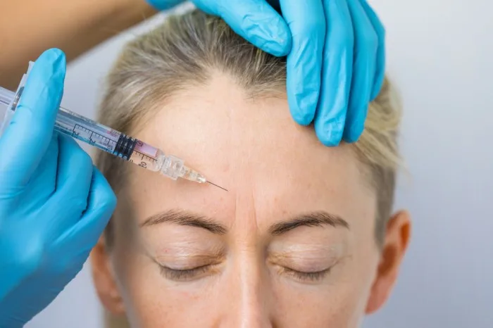 Client receiving Botox for frown lines in a clinical setting.